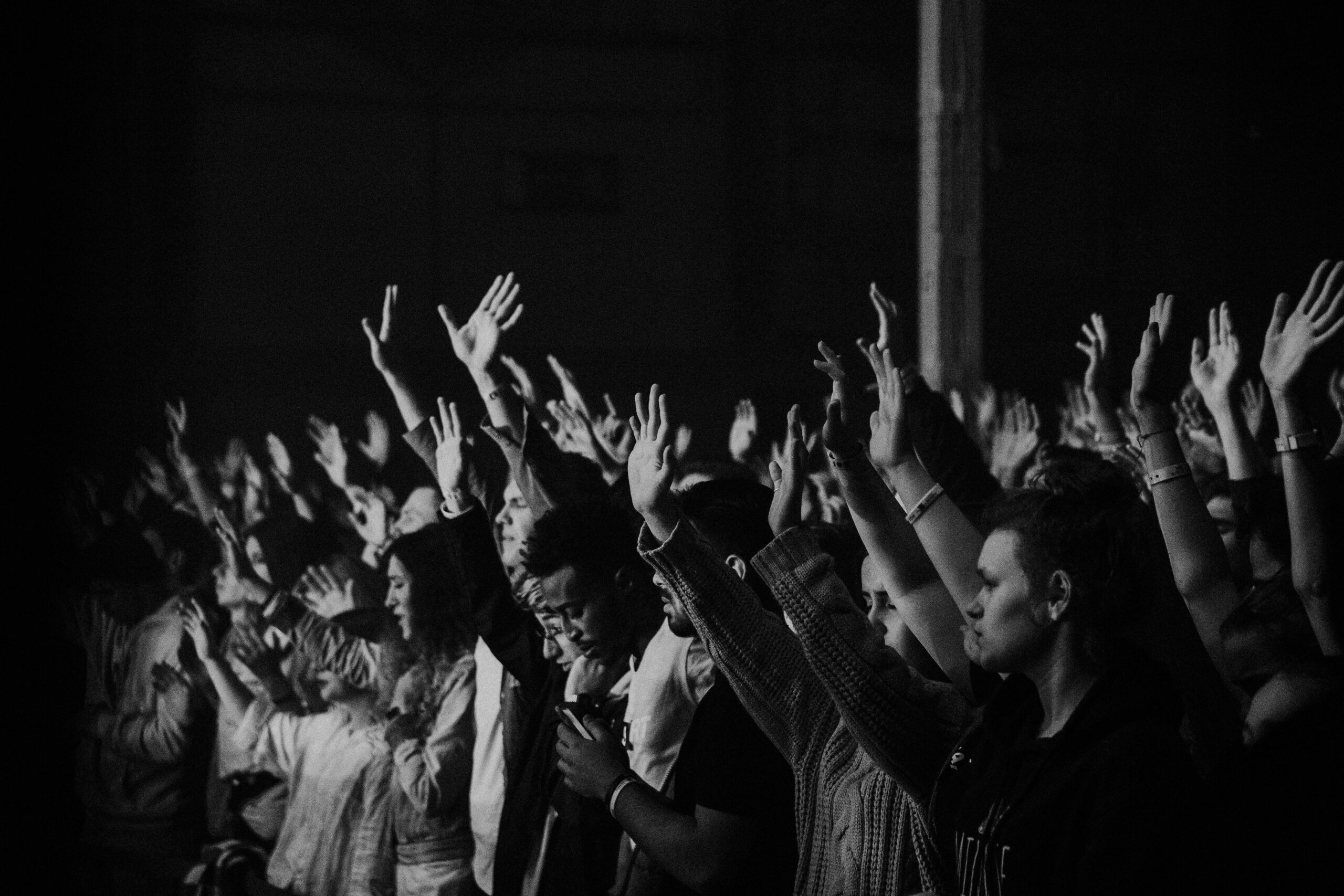 A spiritual community enthusiastically raising their hands together.